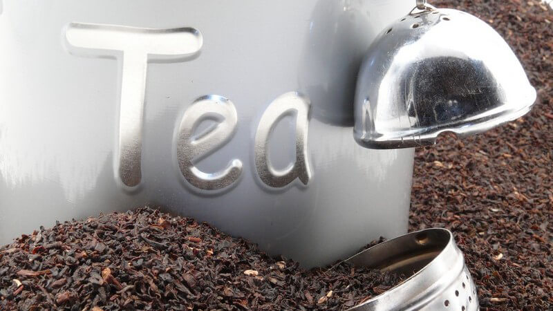 Porzellanduse mit Aufschrift "Tee" steht in getrocknetem Tee