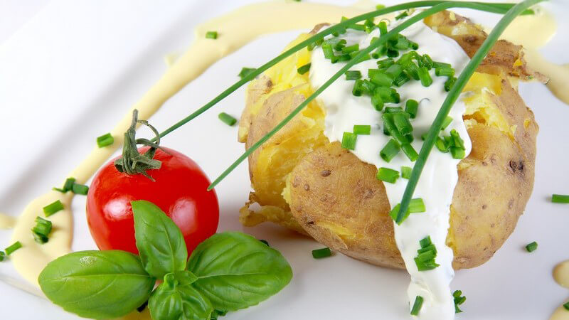Kartoffeln mit Quark und Tomate auf weißem Teller serviert