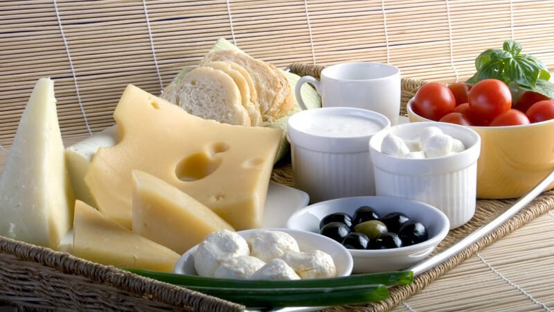 Frühstück auf Tablett: Brot, Käse, Tomaten, Aufstrich, Oliven etc.