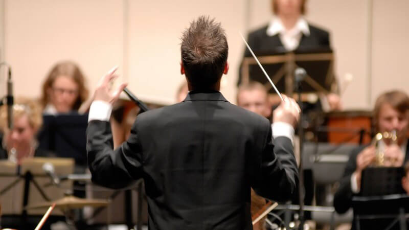 Rückansicht Dirigent dirigiert Orchester
