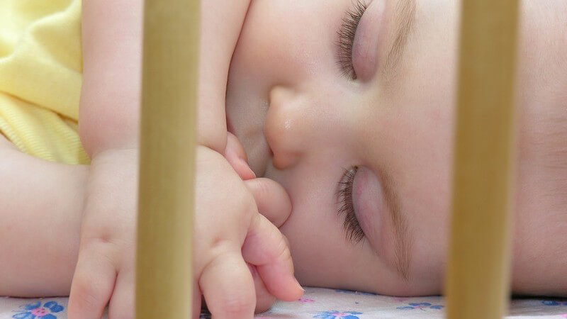 Säugling schläft in Babybett