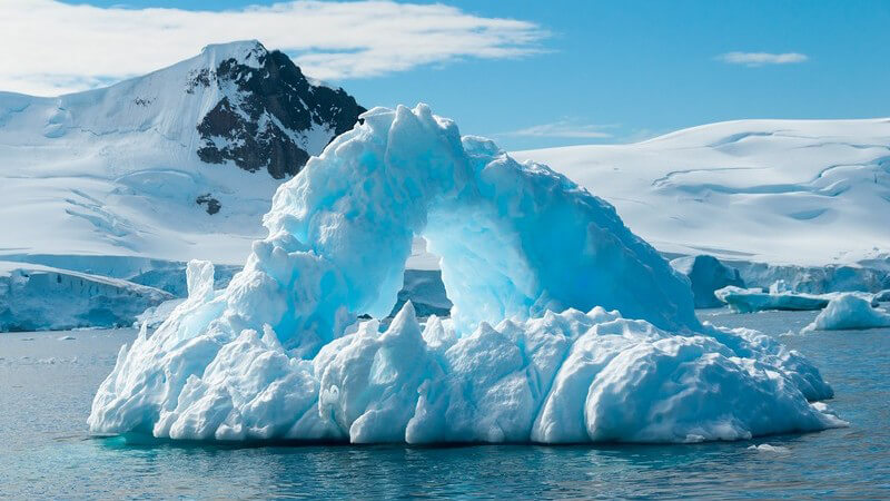 Antarktis: Eisberge im Wasser unter blauem Himmel