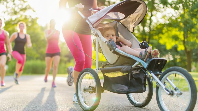 Joggen mit Baby - Frau beim Laufen schiebt Kleinkind im Sport-Buggy