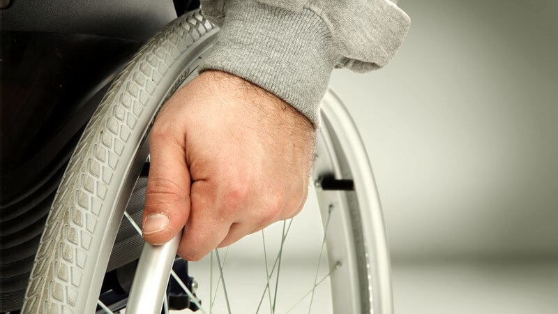 Hand am Rad eines Rollstuhls - Mensch mit Behinderung