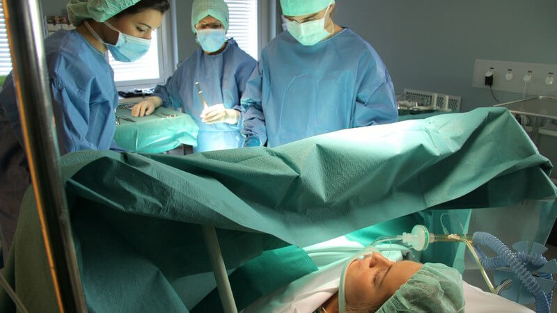 Patientin im Operationssaal wird von drei Ärzten operiert