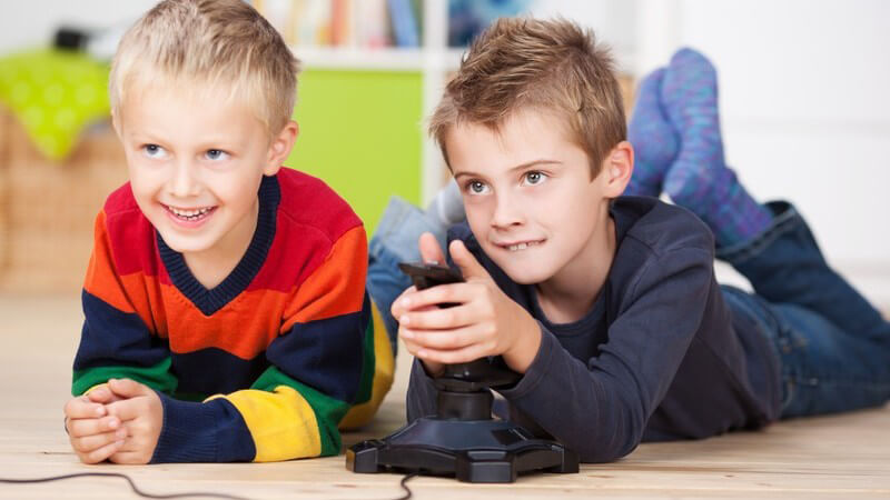 Zwei Jungen liegen auf dem Boden und spielen Videospiel mit Konsole