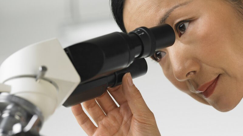 Wissenschaftlerin schaut in Mikroskop