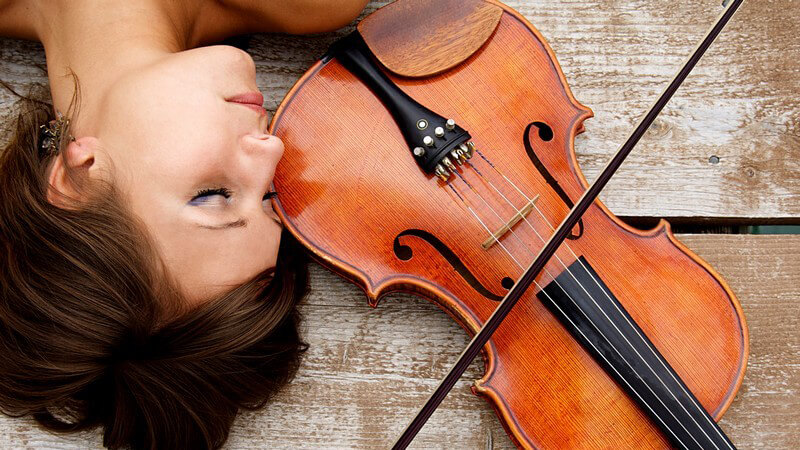 Junge Frau liegt auf Boden, daneben Geige