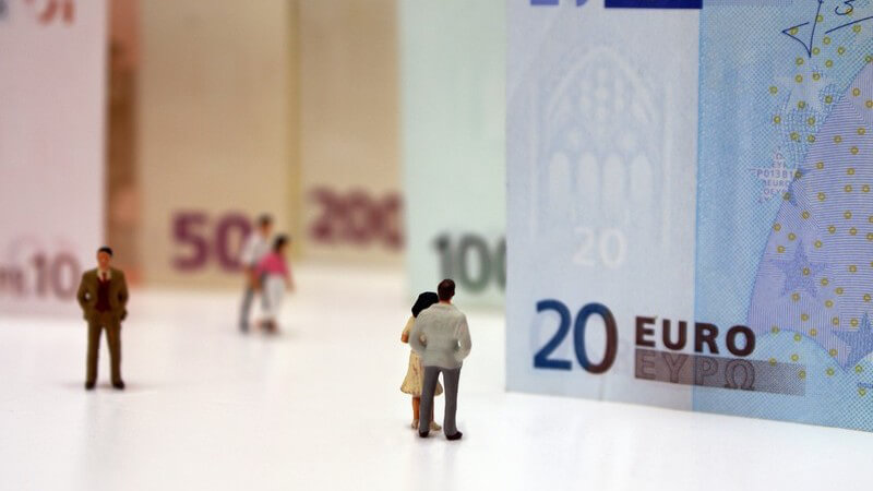 Winzige Personen stehen vor riesigen Euroscheinen