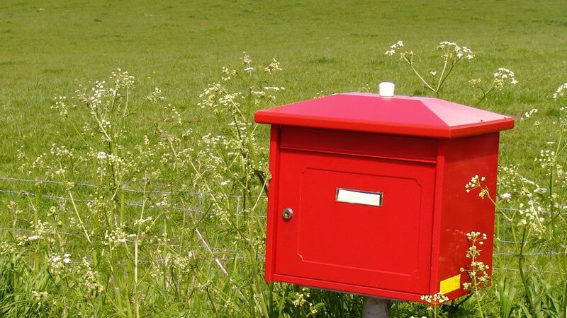 Roter Briefkasten auf grüner Wiese