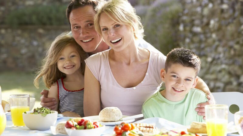 Junge glückliche Familie beim Essen draußen