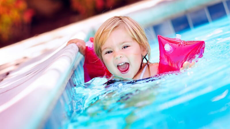 Kleines Mädchen mit Schwimmflügeln im Swimming Pool