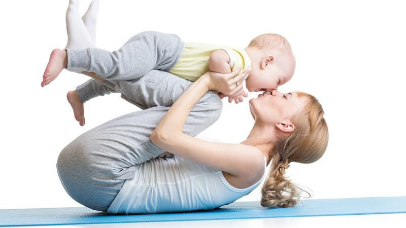 Mutter und Baby bei Fitnessübungen auf einer blauen Yogamatte