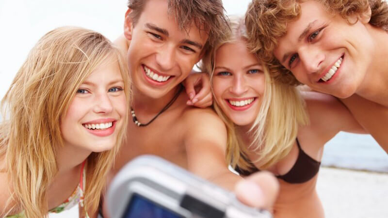 Vier Jugendliche am Strand machen Foto von sich selbst