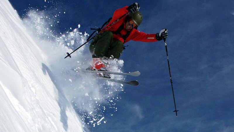 Skifahrer springt steilen Abhang hinunter