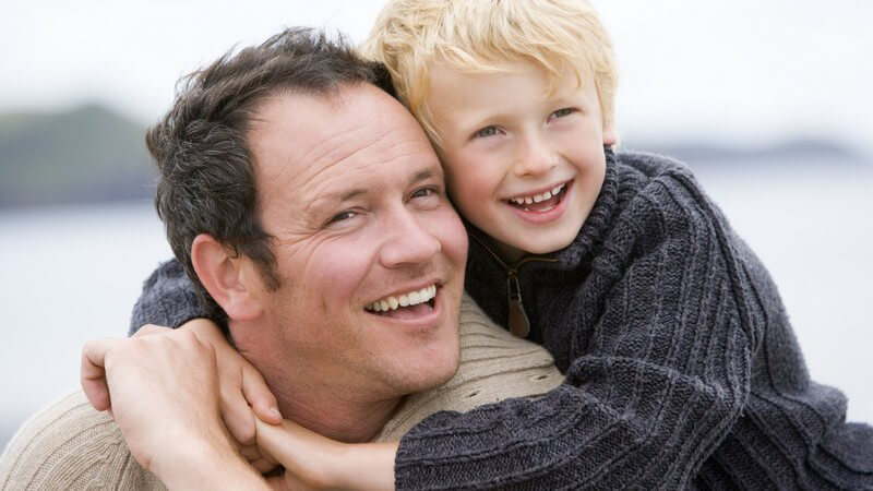 Dunkelhaariger Vater lacht mit seinem blonden Sohn