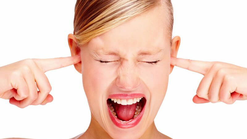 Junge schreiende Frau hält sich die Ohren zu, weißer Hintergrund