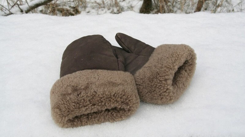 Braune Winterhandschuhe aus Leder mit Fell auf Schnee