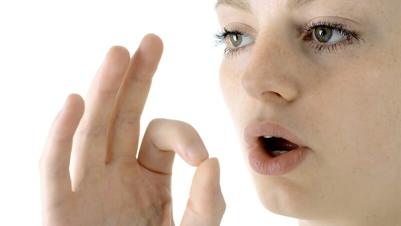 Frau bei einer Sprechtherapie, mit geöffnetem Mund und Fingerzeichen vor weißem Hintergrund
