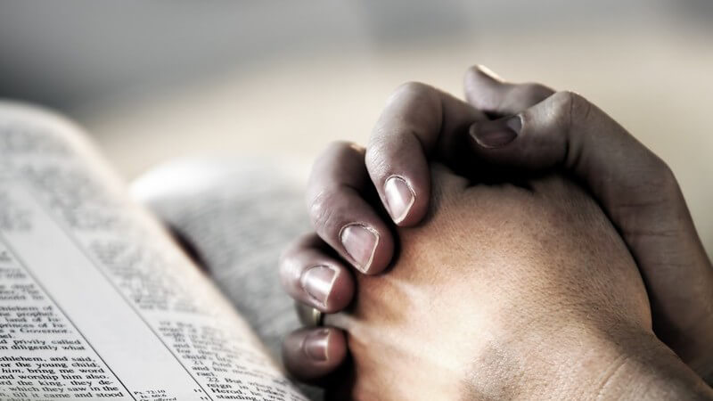 Gefaltete Hände auf einer Bibel