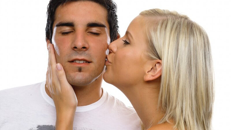 Junge Frau küsst ihren Freund auf die Wange
