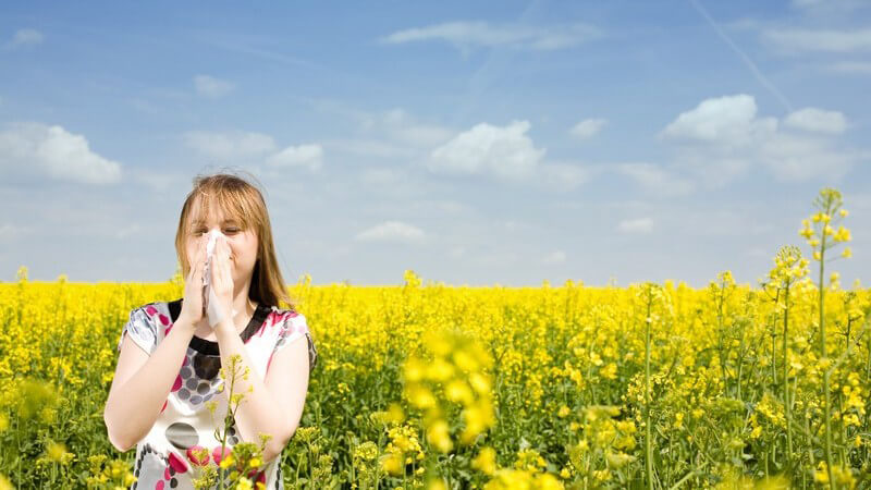 Junge Frau putzt Nase - Allergie Rapsfeld