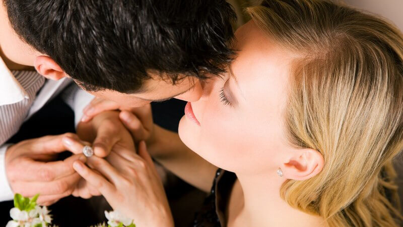 Ansicht von oben: Mann steckt Frau nach Heiratsantrag Finger an, sie küssen sich