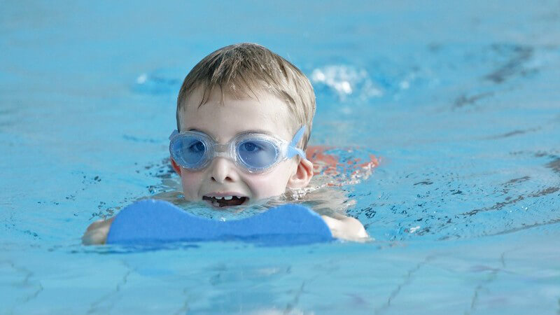 Kleiner Junge mit Taucherbrille und Schwimmhilfe im Wasser
