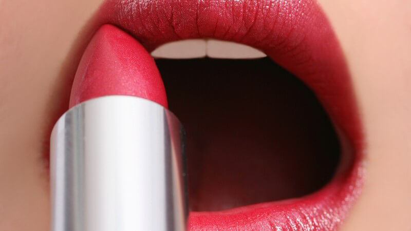 Roter Lippenstift, der auf geöffneten Frauenmund aufgetragen wird