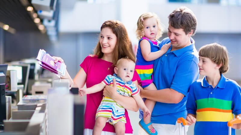 Familie mit drei Kindern beim Check-in am Flughafen