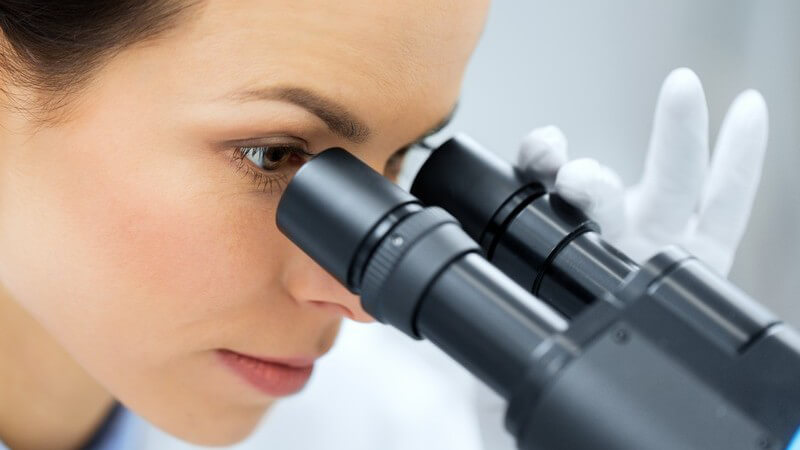 Wissenschaftlerin im Labor guckt in ein Mikroskop