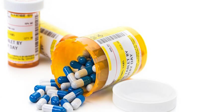 Rezeptpflichtige Medikamente (blau-weiße Kapseln) vor weißem Hintergrund