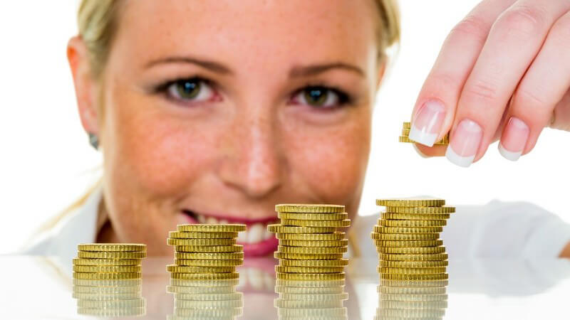 Sparen - Frau legt Geldmünzen aufeinander