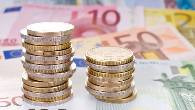 Zwei Stapel mit Euro-Münzen auf Euro-Geldscheinen