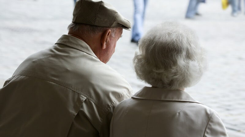 Rückansicht Rentnerpaar sitzt draußen auf Bank
