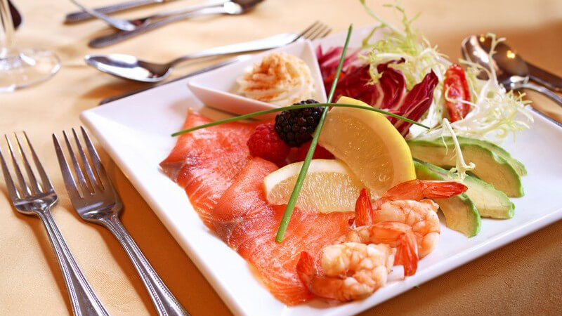 Salat mit Lachs und Shrimps auf weißem Teller