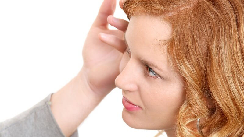 Gesicht einer rothaarigen jungen Frau, wird von einem Handrücken an Wange gestreichelt