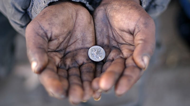 Offene Hände eines Bettlers, darin liegt eine Münze
