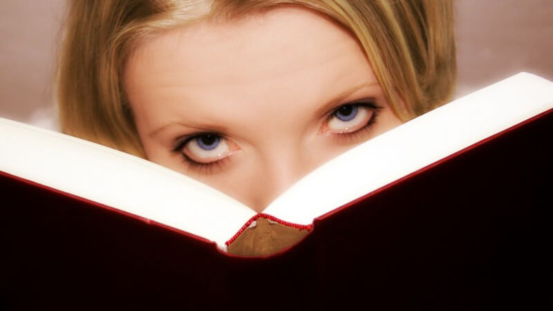 Augen einer jungen Frau, sie schaut aus ihrem Buch hervor