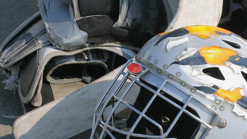 Hockey Ausrüstung auf Betonboden mit Helm, Schutzbekleidung und Hockeyschläger