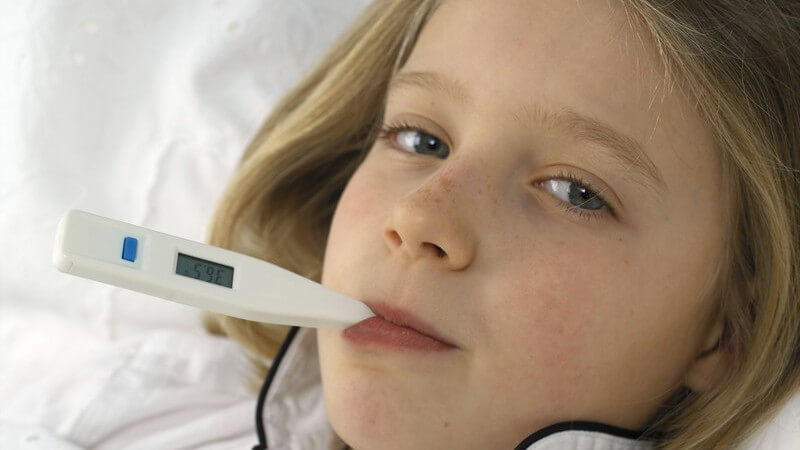 Mädchen im Bett bekommt Fieber gemessen