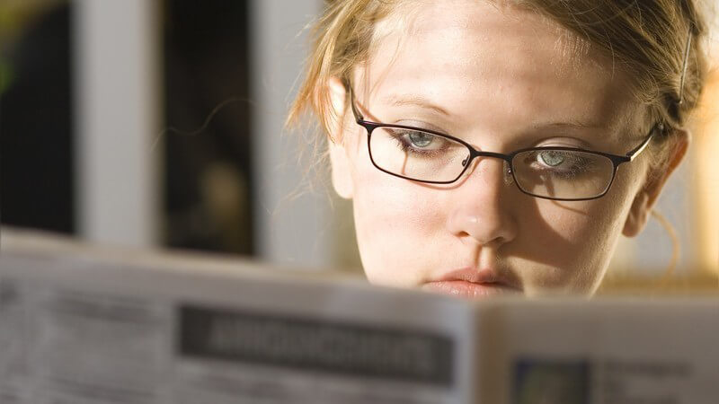 Junge Frau beim Zeitunglesen