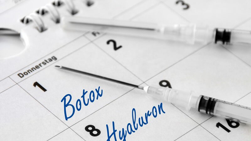 Zwei Spritzen mit Botox und Hyaluron liegen auf einem Terminkalender