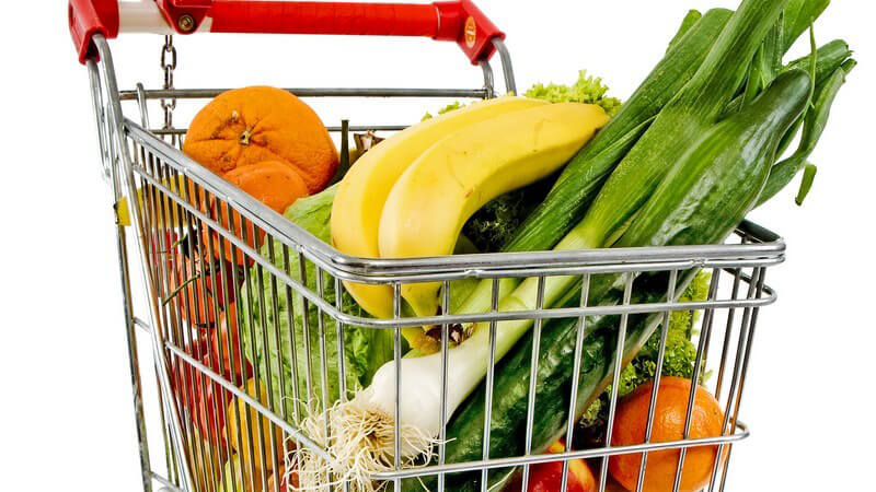 Einkaufswagen mit frischem Obst und Gemüse gefüllt, weißer Hintergrund