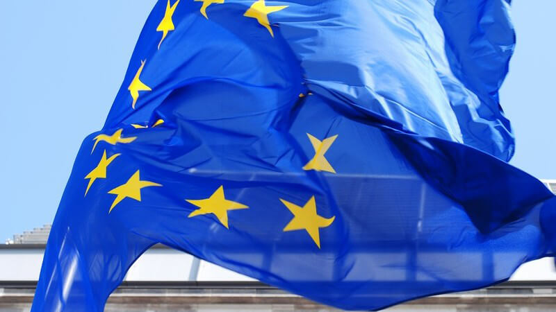 Wehende Europafahne oder EU-Flagge vor Himmel und Haus