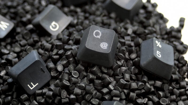 Schwarzes Kunststoffgranulat mit einigen Tasten einer Computertastatur