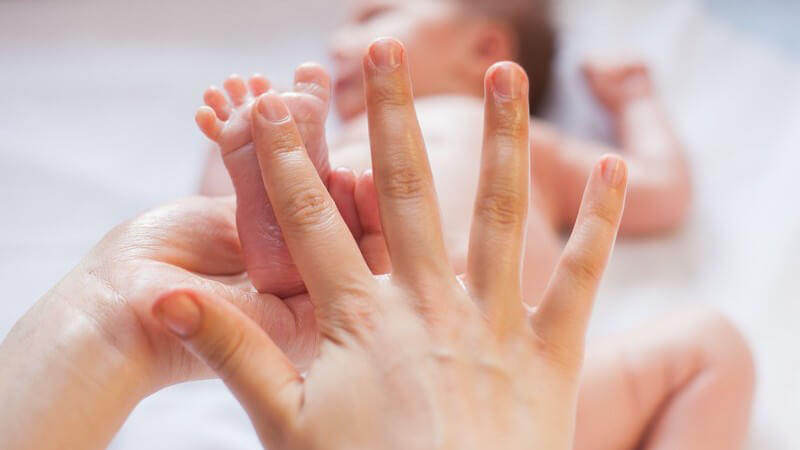 Babymassage mit nur einem Finger am Fuß eines sehr kleinen Säuglings