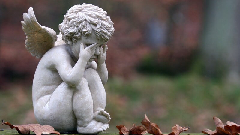 Trauer und Abschied - Engelfigur in trauriger Haltung auf einem Friedhof