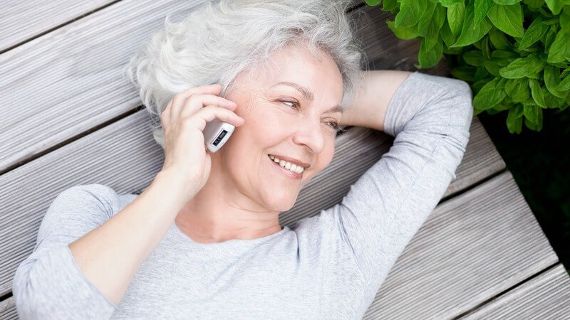 Ältere Frau beim Telefonieren, sie lächelt und sieht glücklich aus