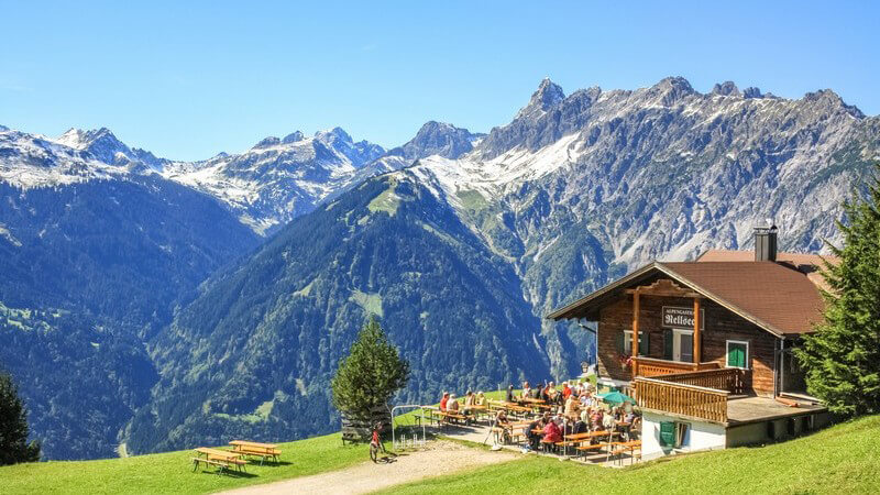 Alpengasthof Rellseck mit Biergarten in Bartholomäberg, Österreich vor wunderschöner Bergkulisse unter blauem Himmel